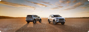 Two Isuzu MU-X SUVs parked on a cracked desert surface at sunset, facing slightly apart.